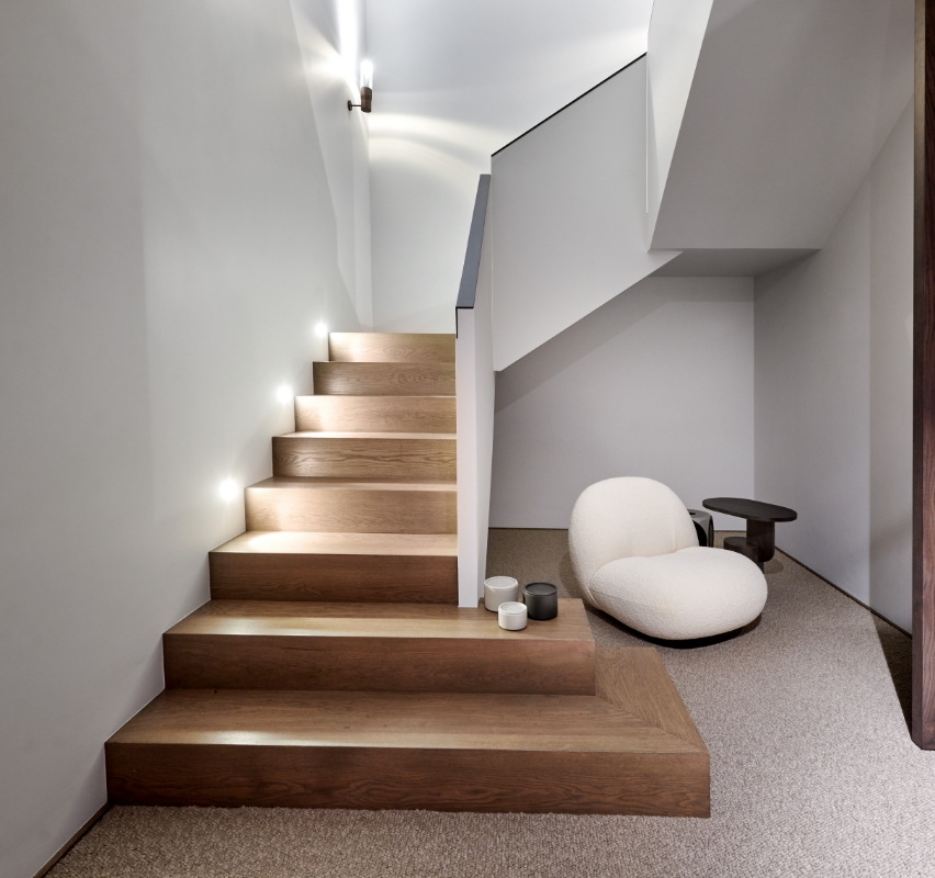 Modern staircase with LED lights and minimalist furniture.